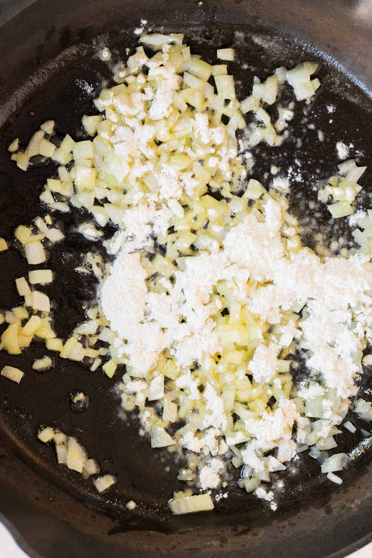 A frying pan with onions and garlic in it.