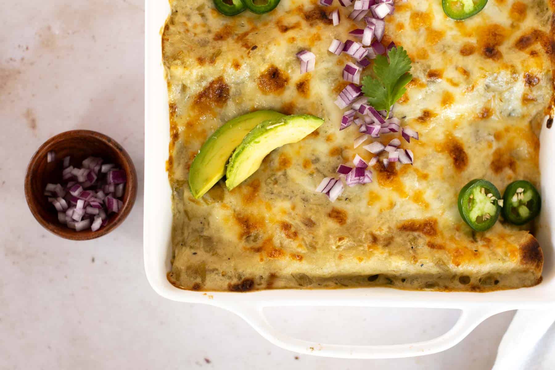 Shredded chicken enchiladas in a casserole dish.
