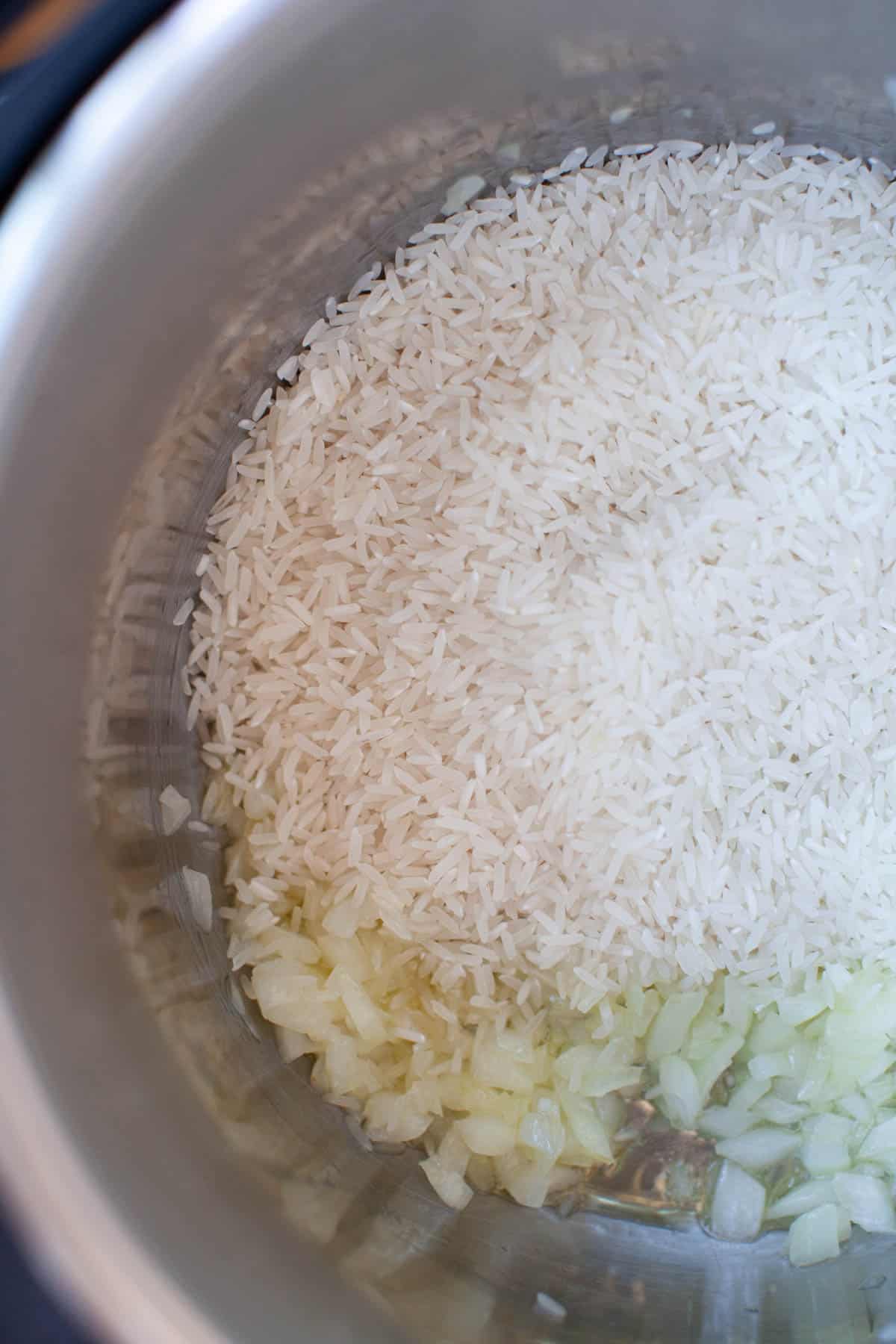 An instant pot filled with rice and saut&eacute;ed onions.