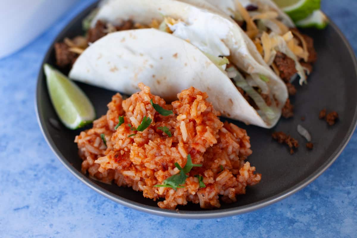 Instant pot Mexican rice on a plate with a lime wedge and tacos.