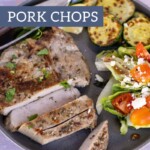 A plate with mouthwatering grilled pork chops, perfectly sliced, accompanied by roasted zucchini and a fresh mixed salad with tomatoes and crumbled cheese. Text overlay reads, "grilled PORK CHOPS.