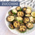 A plate of sautéed zucchini slices with charred edges sits on a striped cloth napkin. Text overlay reads "sautéed zucchini" at the top and "joyfullymad.com" at the bottom.