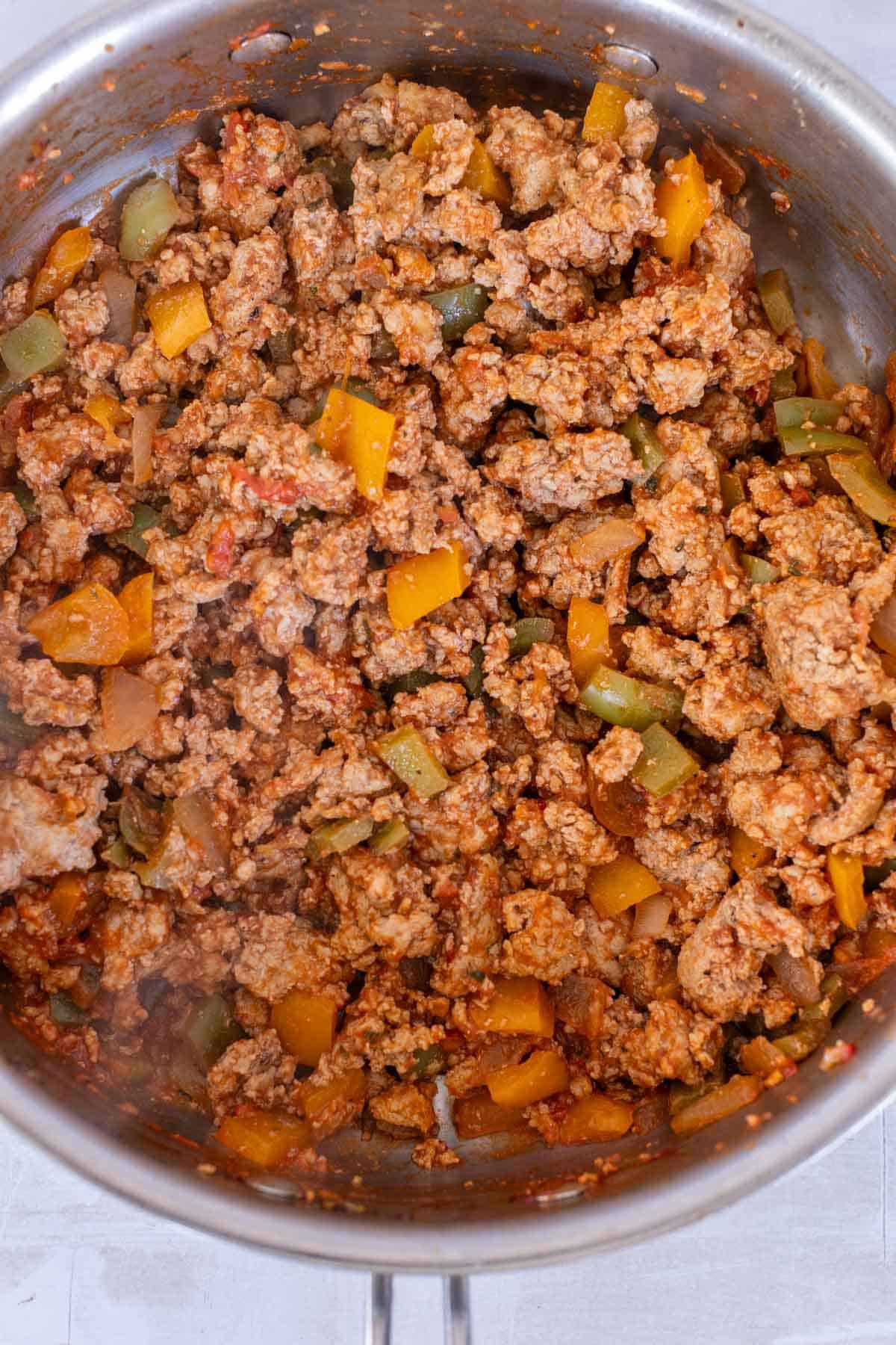 A pot filled with cooked ground turkey, bell peppers, and onions in a tomato-based sauce.
