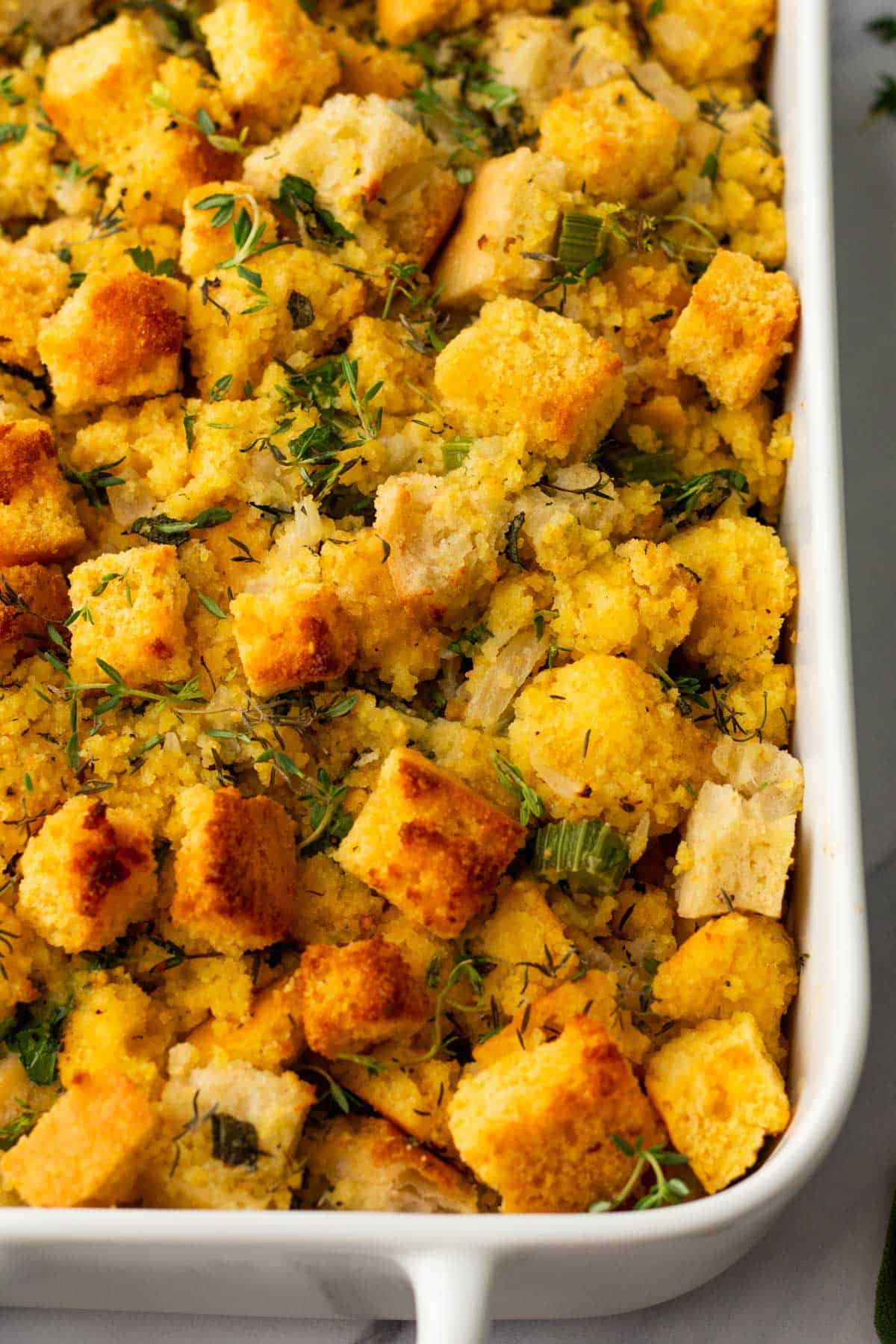 Cornbread stuffing with herbs in a white baking dish.