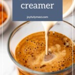 A close-up captures pumpkin creamer gracefully swirling into a glass of coffee, with a bowl of pumpkin subtly enhancing the cozy autumn ambiance in the background.