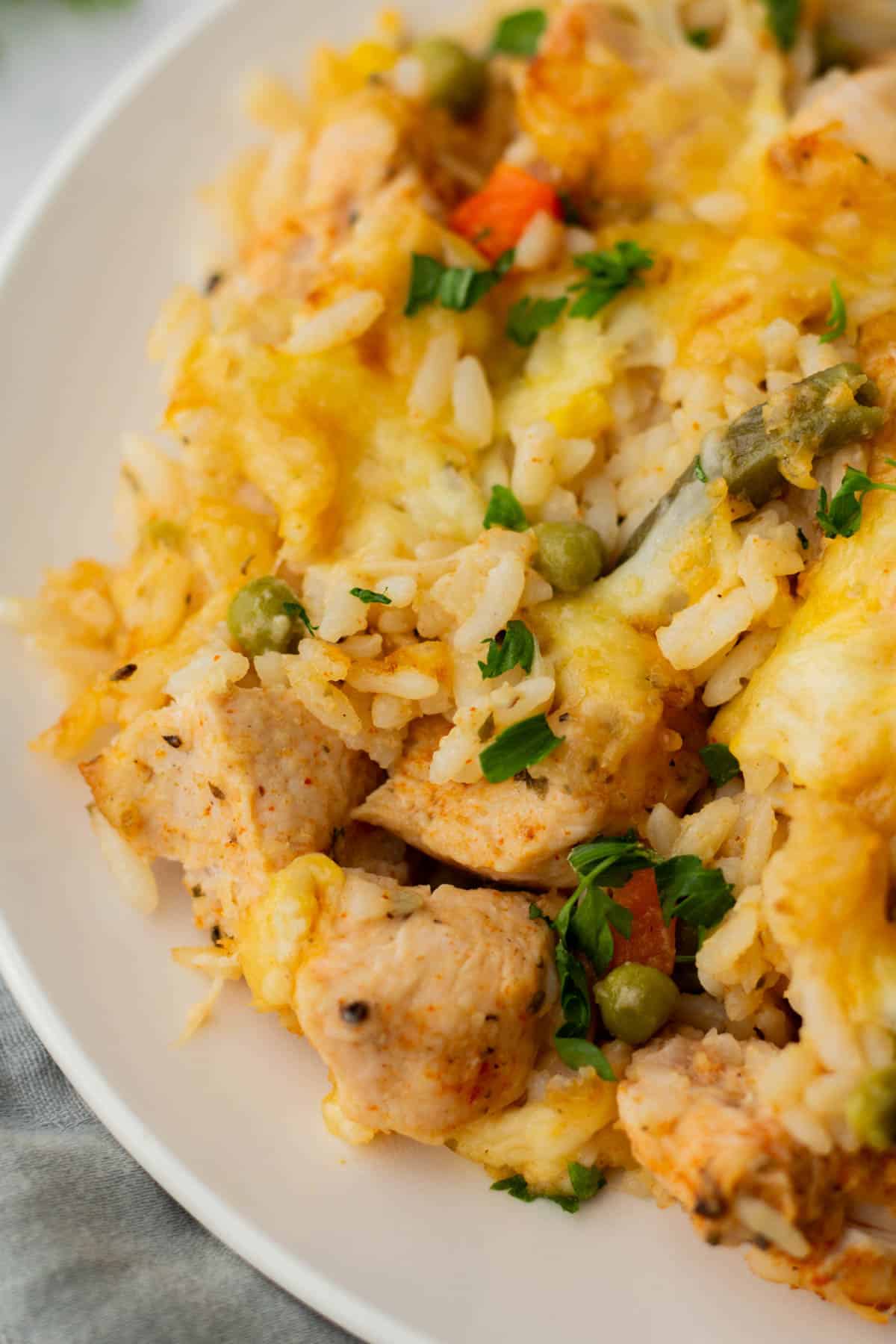 A plate of seasoned rice with pieces of chicken, assorted vegetables, and garnished with fresh herbs.
