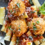 Ricotta meatballs on a bed of rigatoni pasta topped with shredded parmesan and fresh herbs.