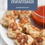 Plate of baked chicken meatballs with a bowl of red sauce on the side.