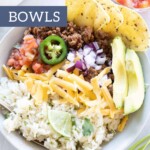 A bowl with rice, baked chicken meatballs, diced tomatoes, jalapeño, red onion, shredded cheese, avocado slices, and tortilla chips is displayed.