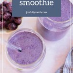Two glasses of vibrant blueberry smoothie, each crowned with a straw, sit beside a small bowl of fresh blueberries and a mint leaf. The text reads "blueberry smoothie joyfullymad.com.