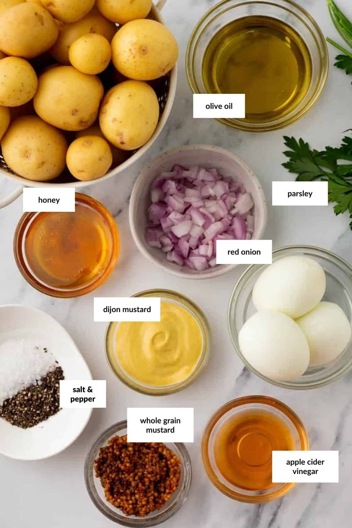 Bowls containing potatoes, olive oil, chopped parsley, honey, red onion, dijon and whole grain mustard, hard-boiled eggs, salt, pepper, and apple cider vinegar&mdash;everything you need for a delicious homemade potato salad dressing.
