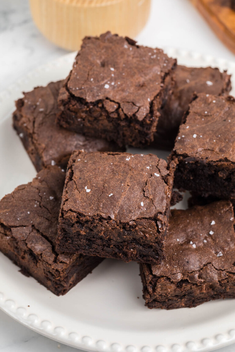 A plate of six chocolate, homemade brownies topped with a sprinkle of coarse salt.