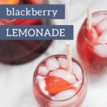 A pitcher and two glasses of blackberry lemonade with sliced peaches and blackberries, shown from above.