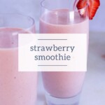 Two glasses of pink strawberry smoothie, one garnished with a fresh strawberry and a clear straw, sit invitingly on a light surface.