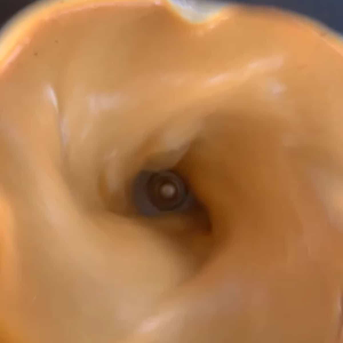 Close-up view of a creamy, light brown mixture being blended in a blender, with the blades visible at the center.