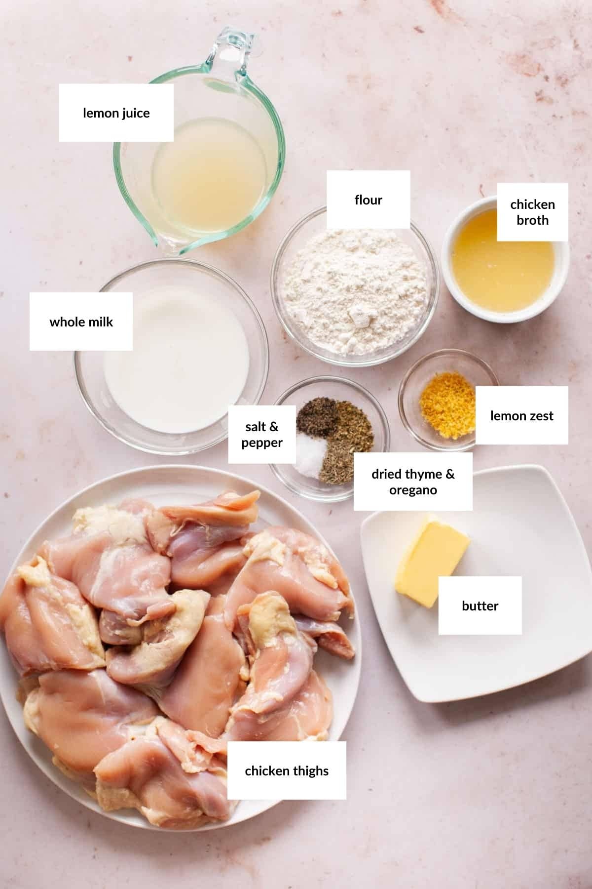 A plate of raw chicken thighs sits beside bowls of flour, chicken broth, lemon juice, whole milk, lemon zest, butter, dried thyme and oregano, salt and pepper&mdash;everything you need to make a flavorful Creamy Lemon Chicken.