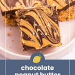 A close-up of chocolate peanut butter rice crispy treats with a swirled chocolate and peanut butter topping, sprinkled with sea salt on a white plate.