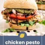 A grilled chicken pesto sandwich with tomato, mozzarella, and arugula on ciabatta bread, displayed on a white surface with balsamic drizzle.