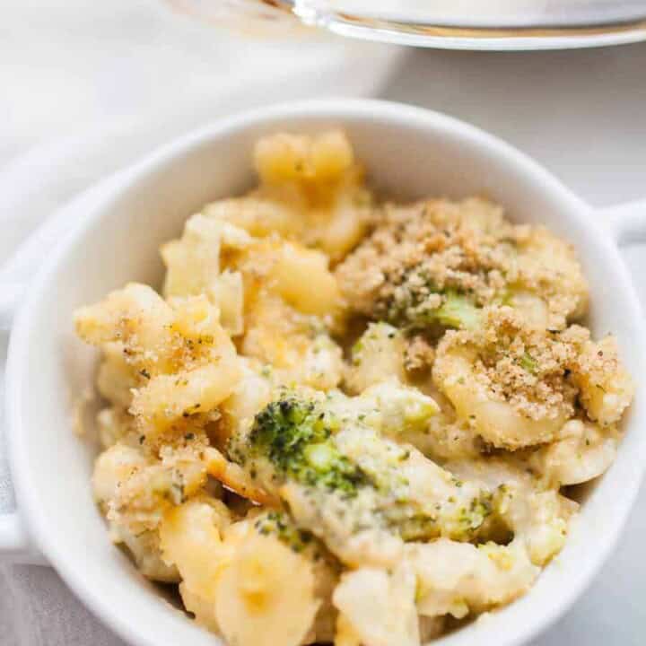 A white bowl filled with macaroni and cheese mixed with broccoli and topped with breadcrumbs.