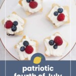 Five star-shaped cupcakes with white frosting, topped with blueberries and raspberries, arranged on a white plate. Text overlay reads "patriotic fourth of July cupcakes.