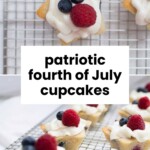 Mini cupcakes topped with whipped cream, raspberries, and blueberries on a wire rack, with text reading "patriotic fourth of July cupcakes.