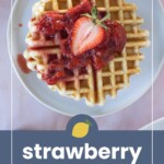 Waffle topped with strawberry compote and a halved strawberry on a white plate, with text "strawberry compote" and a lemon icon below the image.
