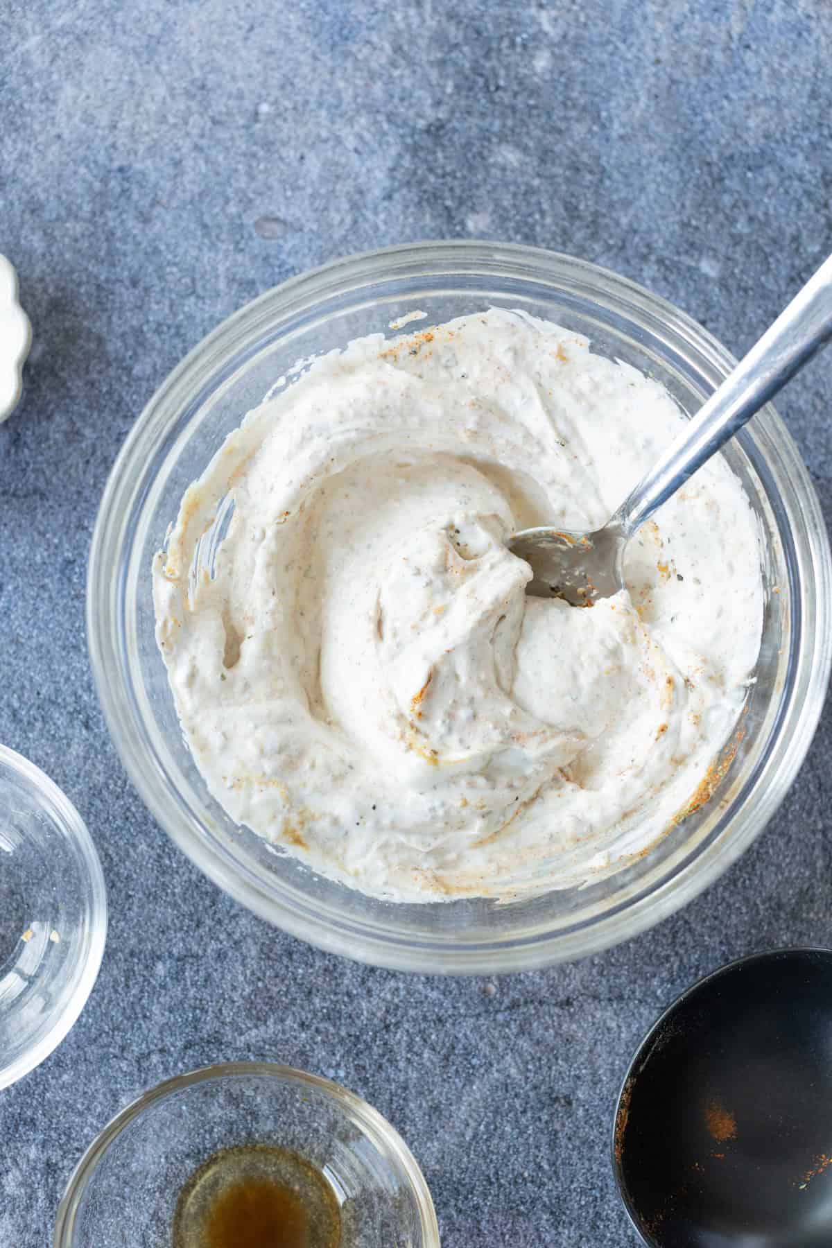 A glass bowl of homemade onion dip and a spoon.