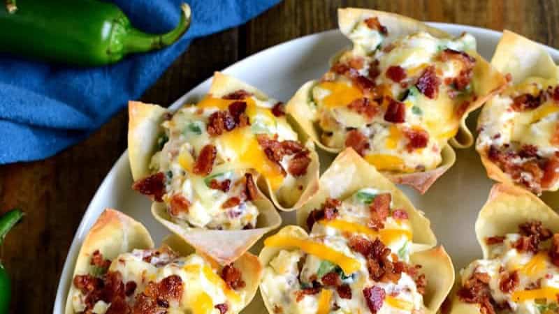 Wonton cups filled with a creamy mixture, topped with melted cheddar cheese and bacon bits.